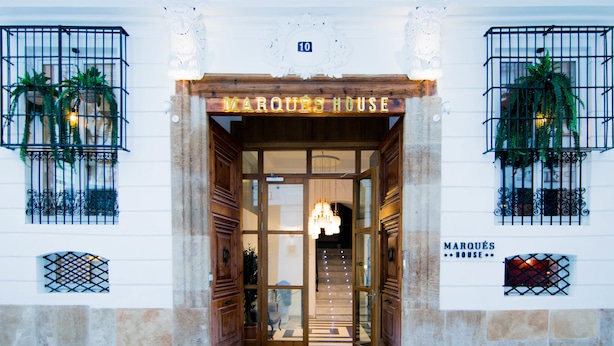 The entrance to Marquês House with a wooden facade, glass doors, and a chandelier. - MYR Marqués House Hotel (Valencia)
