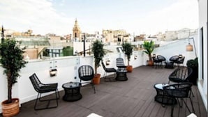 A rooftop terrace with outdoor seating, potted plants, and a view of the cityscape. - MYR Marqués House Hotel (Valencia)