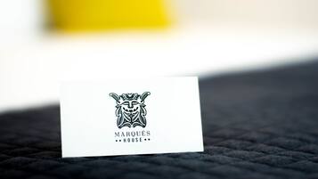 Tarjeta de presentación con un logotipo estilizado de máscara y el texto “MARQUÉS HOUSE”.