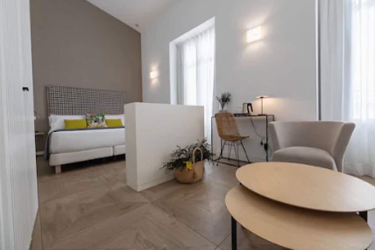 A modern living room with a sofa, a round table, and a bed with a headboard.