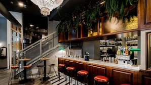 A bar area with a staircase, wooden bar counter, and red stools. - MYR Marqués House Hotel (Valencia)
