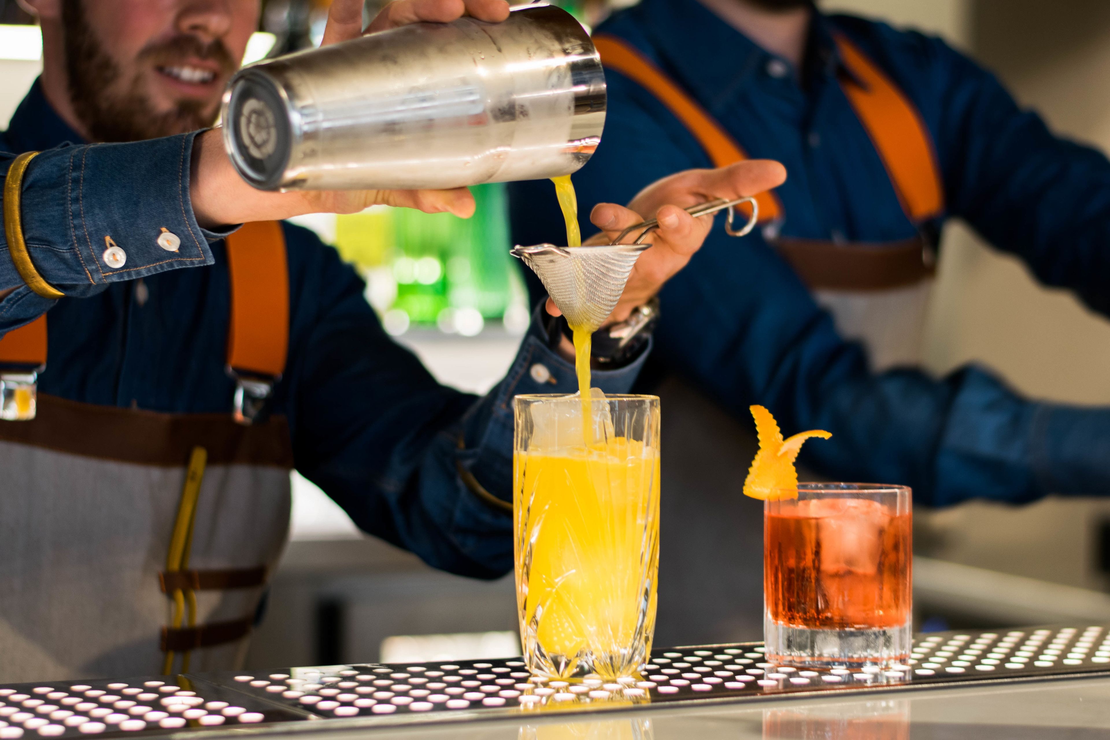 Um bartender servindo uma bebida em um copo alto.