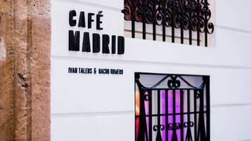 Un letrero anuncia Café Madrid, con una reja de hierro forjado y un muro de piedra.