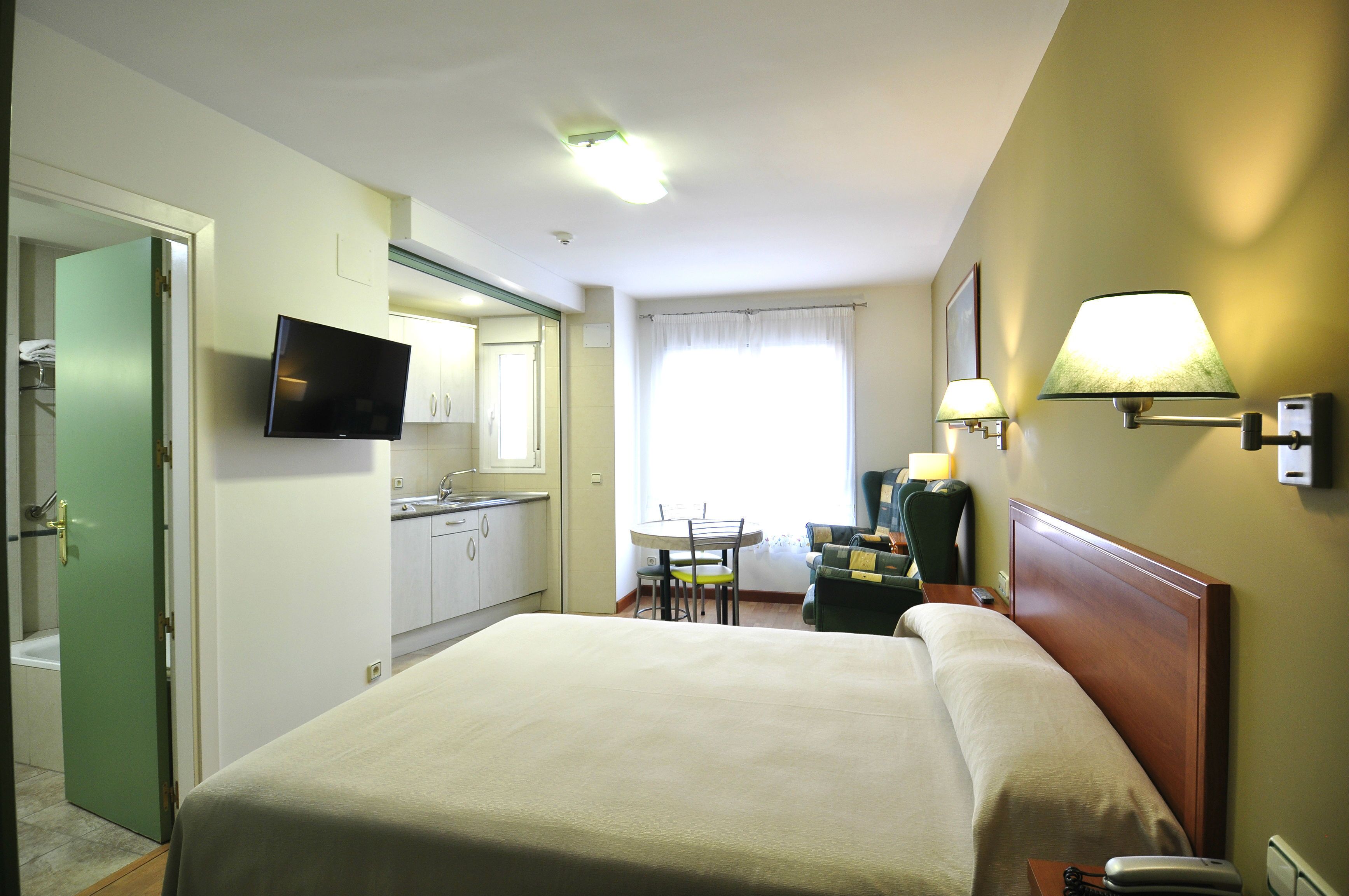 Hotelkamer met een bed, een bureau met stoel, een televisie en een badkamer met toilet en wastafel.