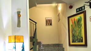 Una escalera con barandilla, una luz empotrada en la pared y un cuadro enmarcado.