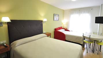 A hotel room with two beds, a dining area, and a television.