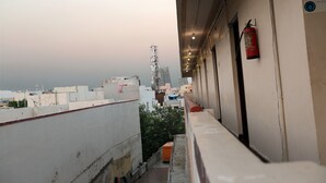 A balcony with a fire extinguisher, a view of the cityscape, and a building with a sign. - Hotel Boopathi (Madurai)