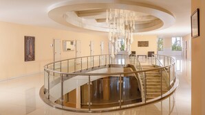 A spacious, modern interior with a central spiral staircase, a glass railing, and a ceiling with a unique light fixture. - Chinar Health Hotel Naftalan (Naftalan)