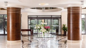 A lobby with a glass-top table, large wooden columns, and a view of greenery outside. - Chinar Health Hotel Naftalan (Naftalan)