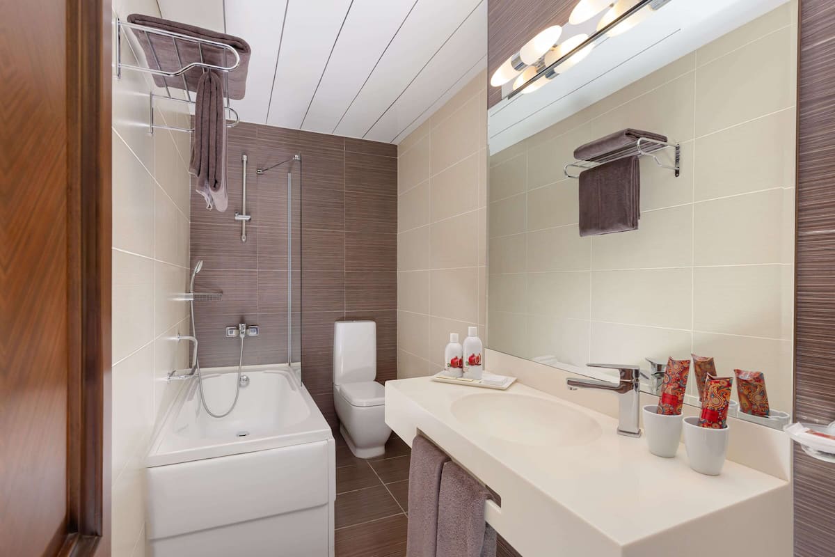 Uma casa de banho moderna com banheira, chuveiro, sanita e lavatório com espelho.