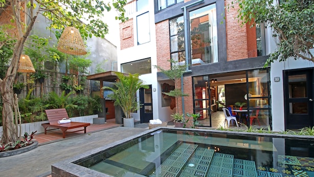 A modern building with a swimming pool, outdoor seating, and potted plants. - Country Inn (Siem Reap)