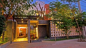 A modern building with a well-lit entrance, a covered porch, and a garden area. - Country Inn (Siem Reap)