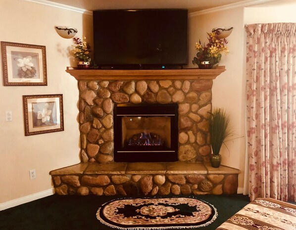 Una chimenea de piedra con un televisor de pantalla plana en la parte superior, enmarcada por dos arreglos florales.