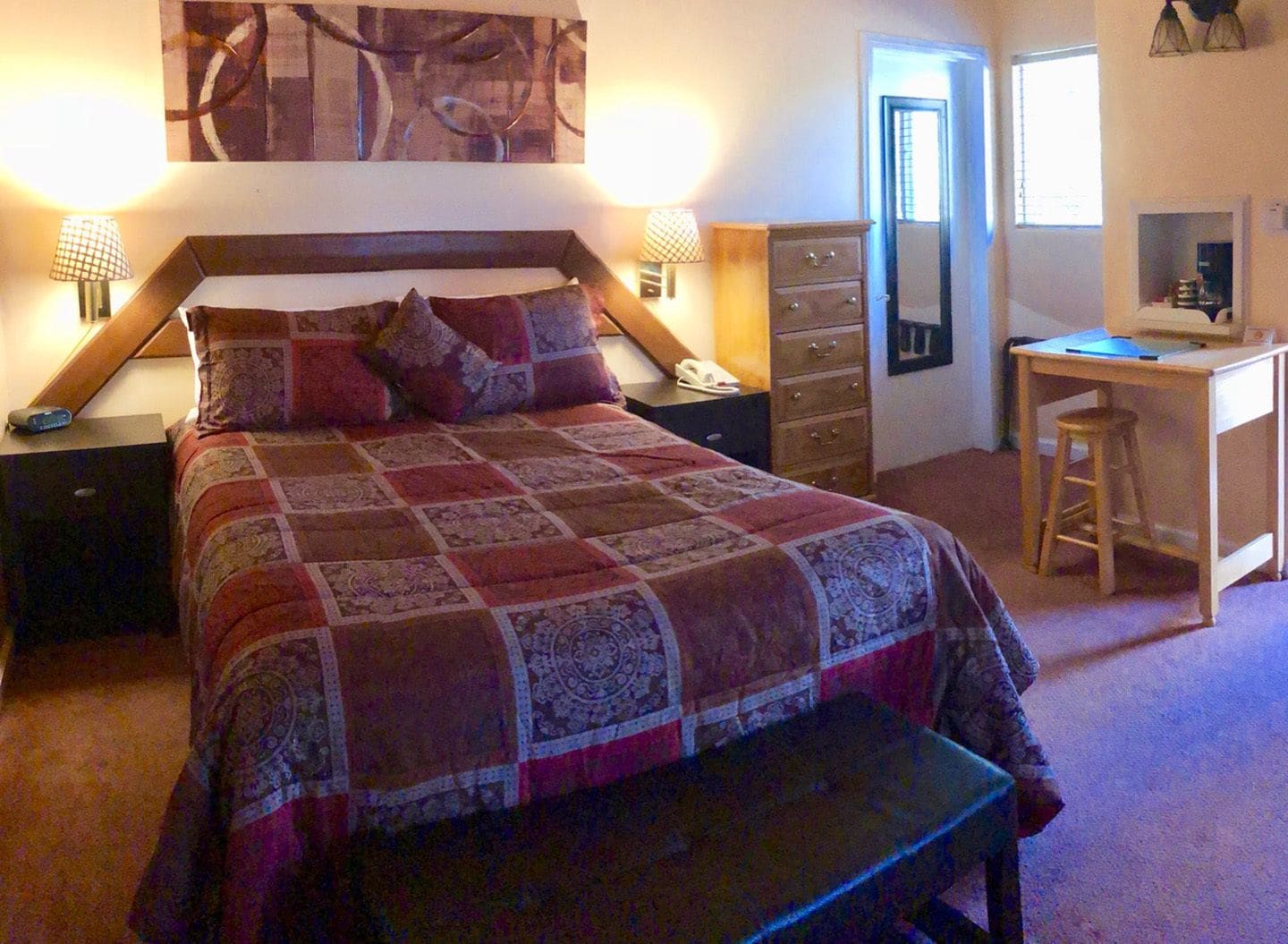 A bedroom with a large bed, bedside tables, a desk, and a chair.