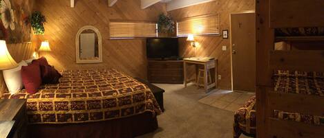 A bedroom with a large bed, a television, a desk, and a bunk bed.