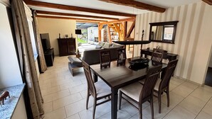 A dining area with a wooden table and chairs, a television mounted on the wall, and a view of the outdoor patio. - Landgasthof Kleine Kommode (Walkenried)
