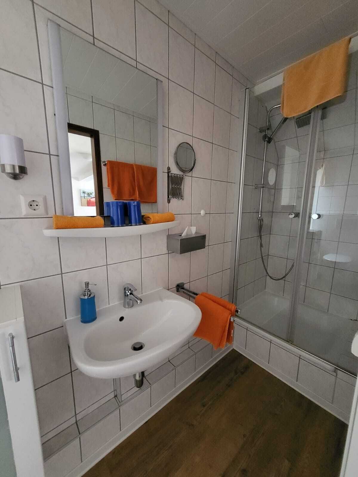A modern bathroom with a white sink, mirror, and shower.