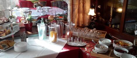 A dining area with tables set for breakfast, including plates, cups, and a variety of food items.