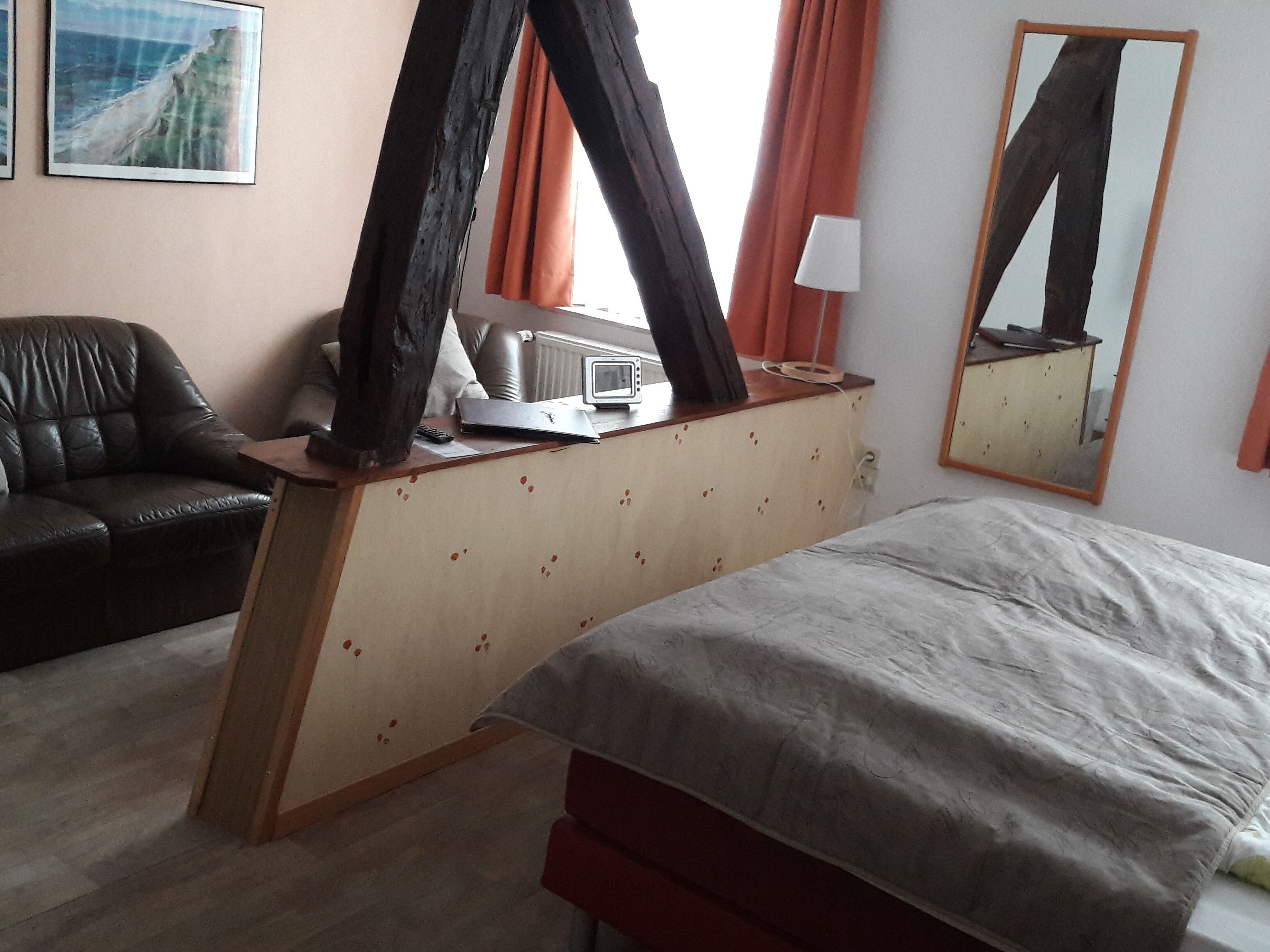 A bedroom with a bed, a desk with a laptop, a chair, and a mirror.