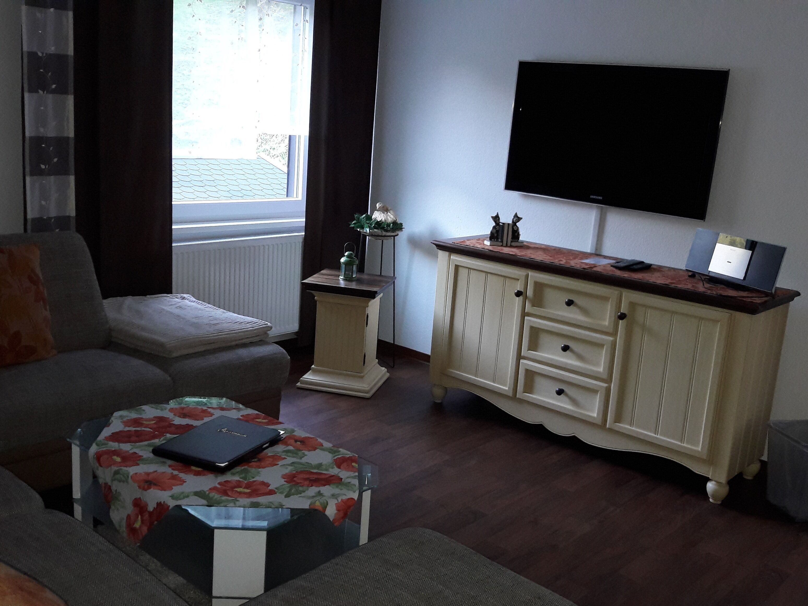 A living room with a sofa, a coffee table, a cabinet, and a television mounted on the wall.