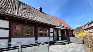A traditional building with a tiled roof, a staircase leading to the entrance, and a clear sky. - Landgasthof Kleine Kommode (Walkenried)