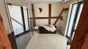 A bedroom with a bed, a wooden beam ceiling, a glass door, and a tiled floor. - Landgasthof Kleine Kommode (Walkenried)