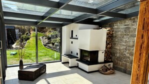 Una sala de estar moderna con chimenea, ventanas amplias y vista a un jardín.