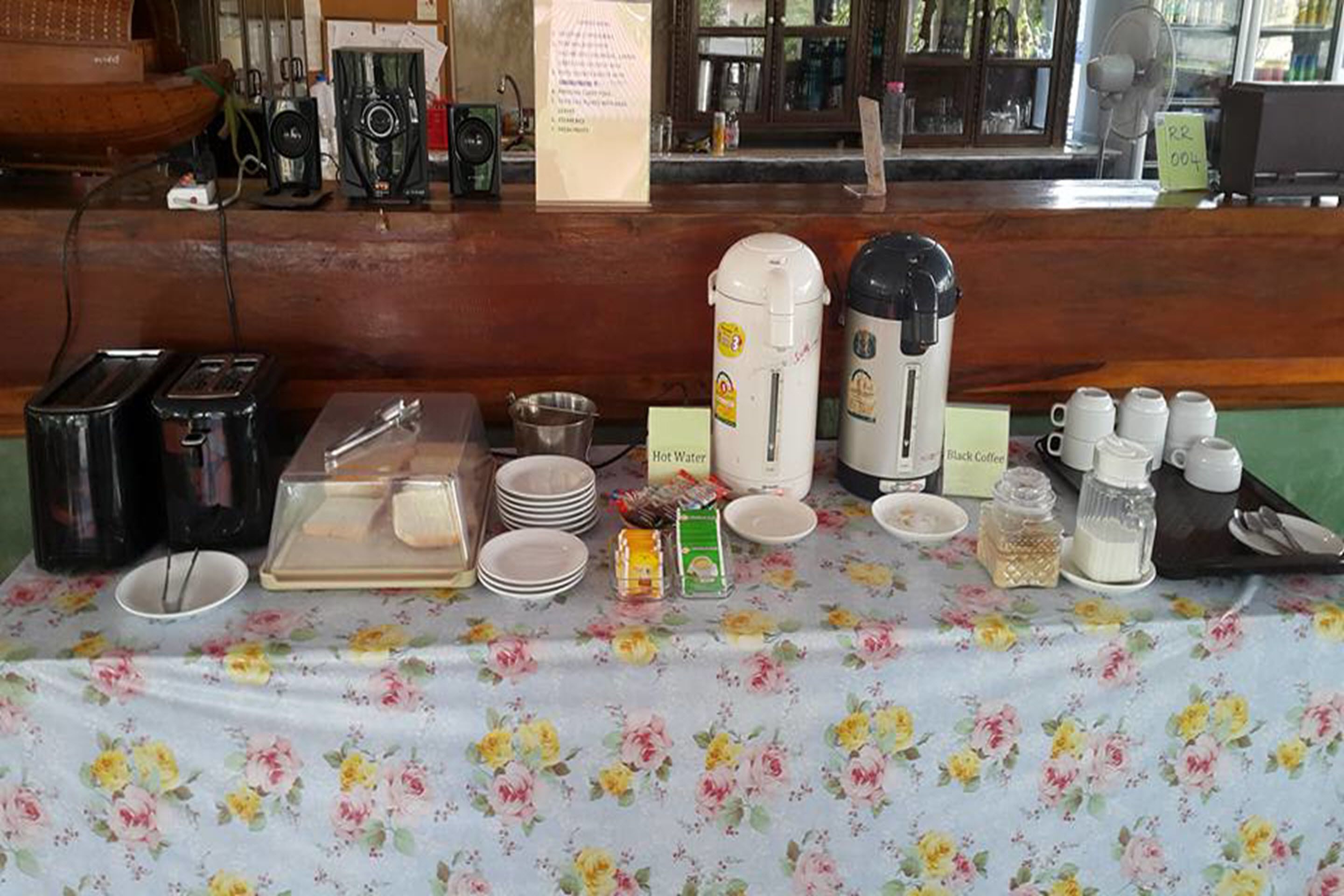 A breakfast buffet setup with various food items and beverages, including hot water, coffee, and condiments.