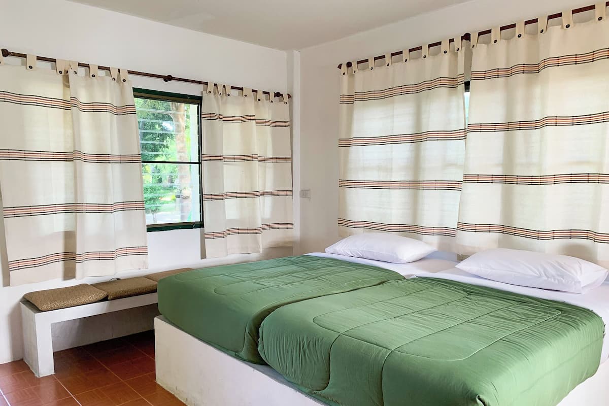 A bedroom with a bed, curtains, and a window.