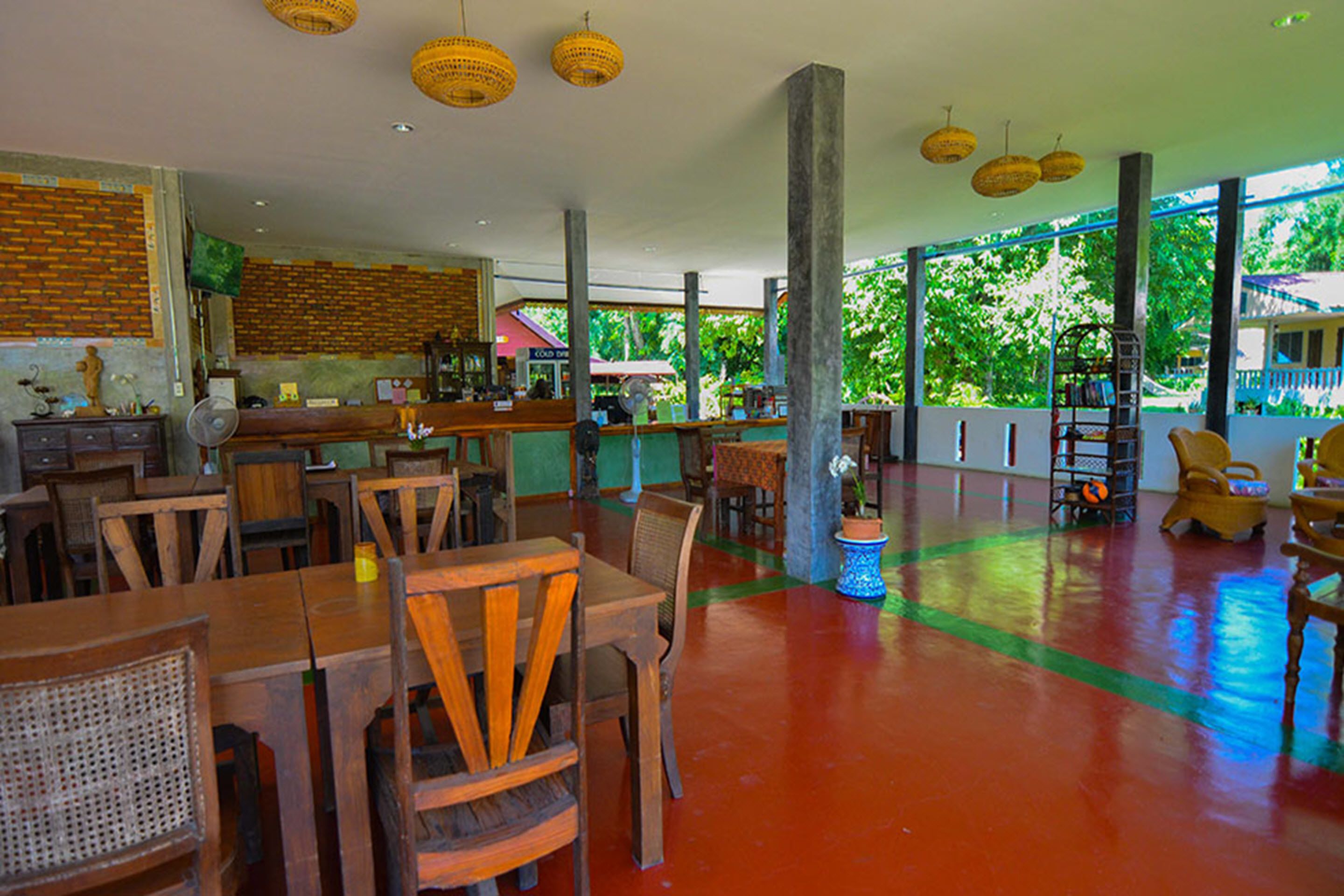 A spacious indoor area with wooden tables and chairs, a bar area, and large windows allowing natural light.