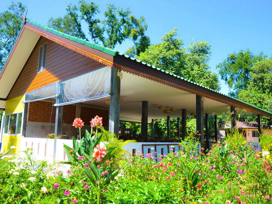 A two-story building with a covered porch and a garden in front.