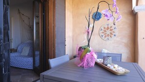 Une terrasse avec une table, des chaises et une composition florale décorative à base d’orchidées.