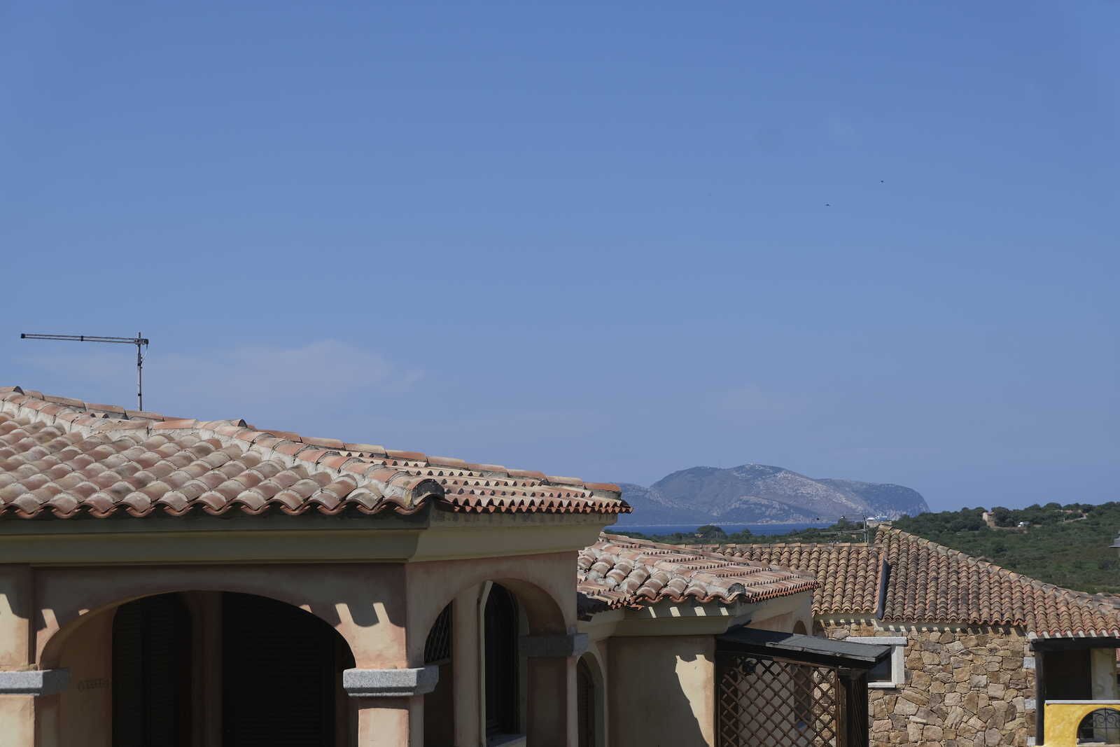 Un edificio con tejado de tejas y paredes de piedra, con arcos en las puertas y una antena visible.