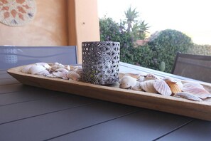 A wooden tray with seashells and a decorative glass container on a table.