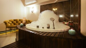 Une salle de bain moderne avec une baignoire sur pieds, un canapé jaune et un éclairage décoratif.