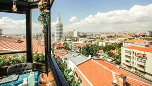 Un balcon offrant une vue sur le paysage urbain, avec notamment une tour imposante et divers bâtiments.