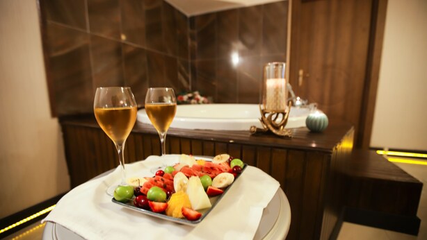 Un plateau contenant un assortiment de fruits et deux verres de vin, posés sur une table dans une salle de bain moderne.