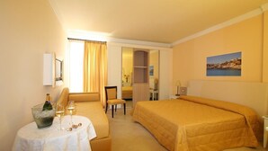 Une chambre d’hôtel avec un lit, une petite table sur laquelle se trouvent une bouteille et des verres, une chaise et un bureau.