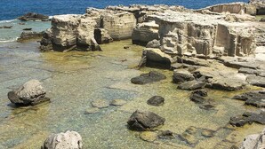 Un site archéologique situé sur la côte, avec des ruines anciennes et des eaux cristallines.