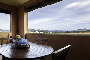 Mesa de madeira com arranjo floral em uma varanda com vista para montanhas e edifícios ao longe.