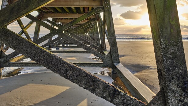 Estrutura de cais com vista para a praia e o oceano.