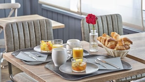 Uma mesa de madeira com cadeiras e uma cesta de croissants para o café da manhã.