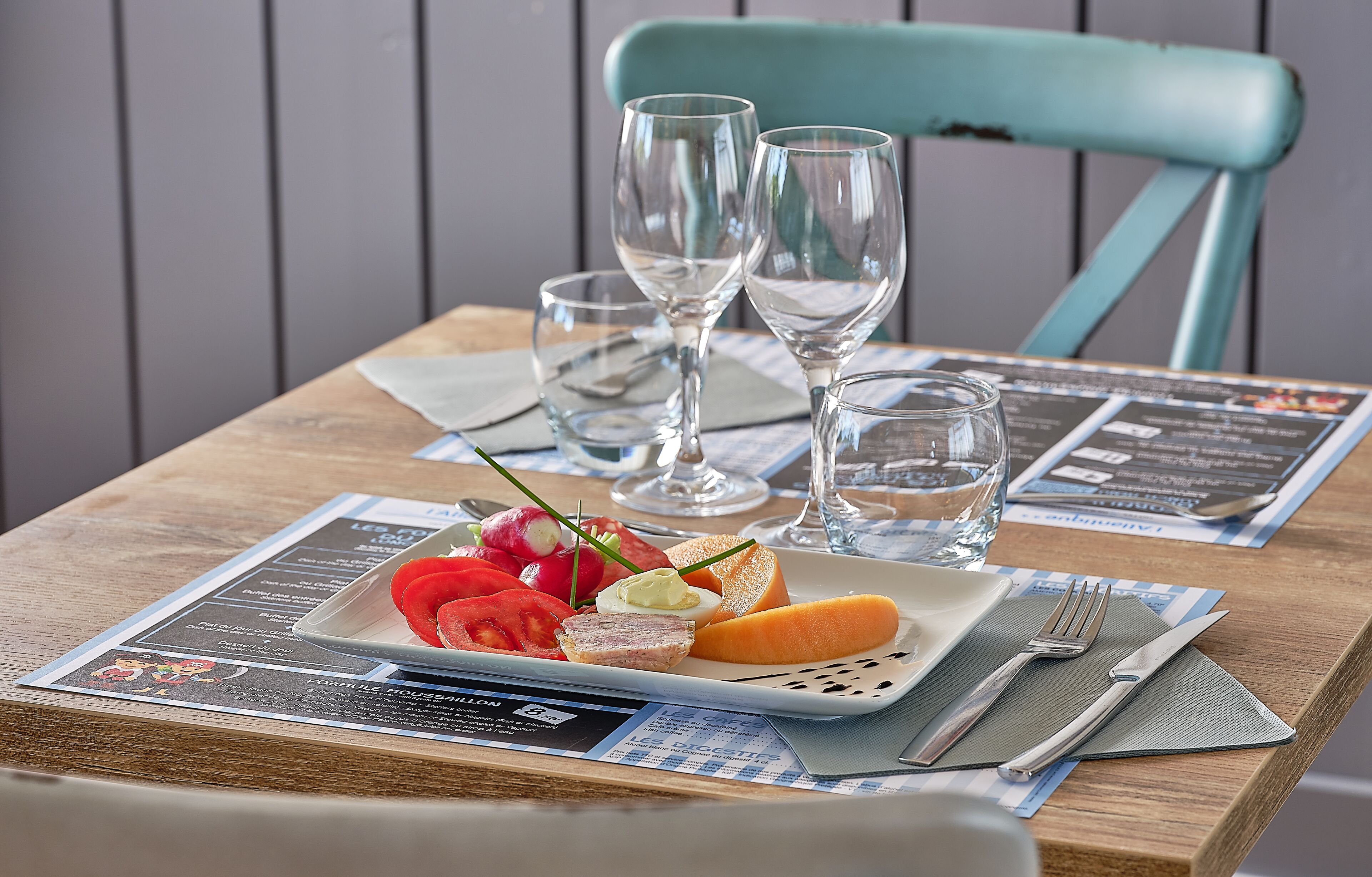 A table set with a plate of food, cutlery, and two glasses of water.