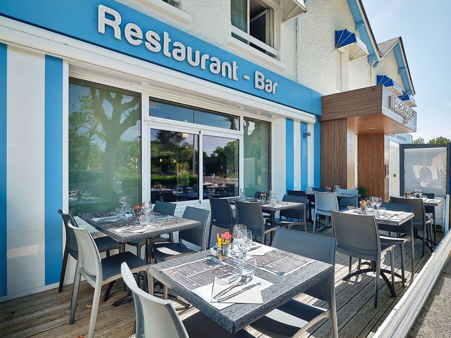 Een terras van een restaurant met tafels en stoelen, een helder uitzicht op de straat, en een bord met de tekst
