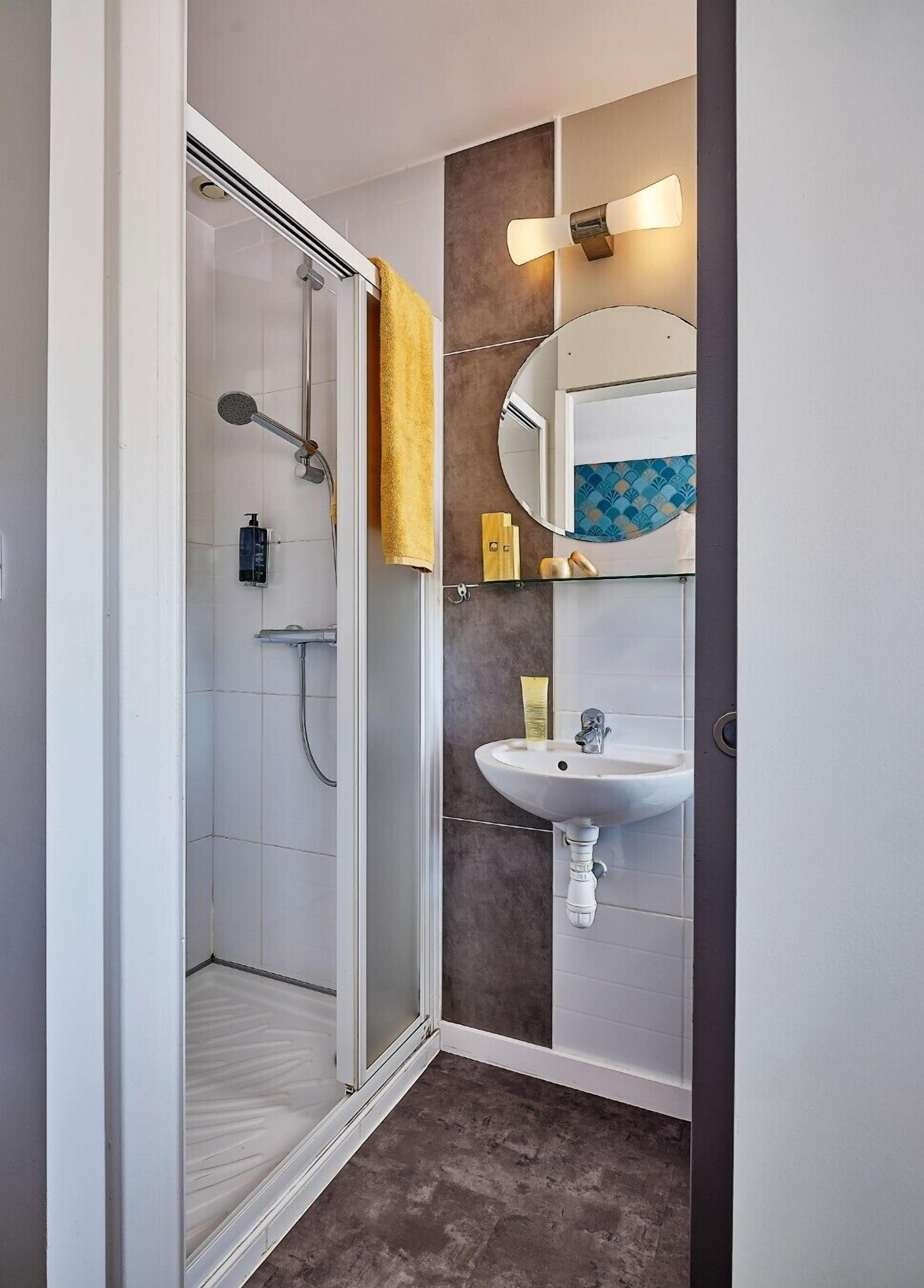 A modern bathroom with a glass shower enclosure, a white sink, and a mirror with a decorative backsplash.
