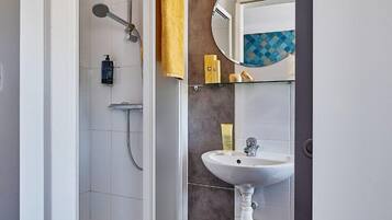 A modern bathroom with a glass shower enclosure, a white sink, and a mirror with a decorative backsplash.