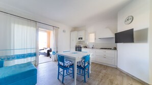 Un espacio habitable compacto con una mesa de comedor, dos sillas, un sofá, una zona de cocina y un balcón.