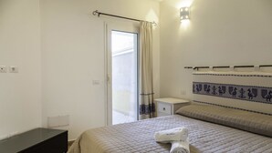 Una habitación de hotel con cama, mesita de noche y ventana con cortinas.