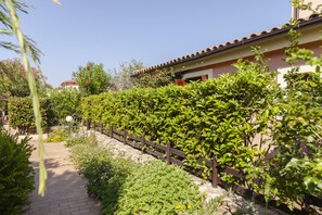Un chemin de jardin qui mène à un bâtiment doté d’un toit en tuiles et d’une clôture en bois.