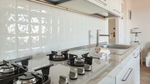 A modern kitchen with white tiled backsplash, stainless steel appliances, and a built-in oven. - Aria di Vacanza - S'Abba Lughente (Olbia)